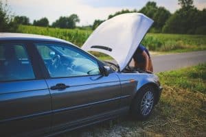 Driver awaiting roadside assistance with hood lifted