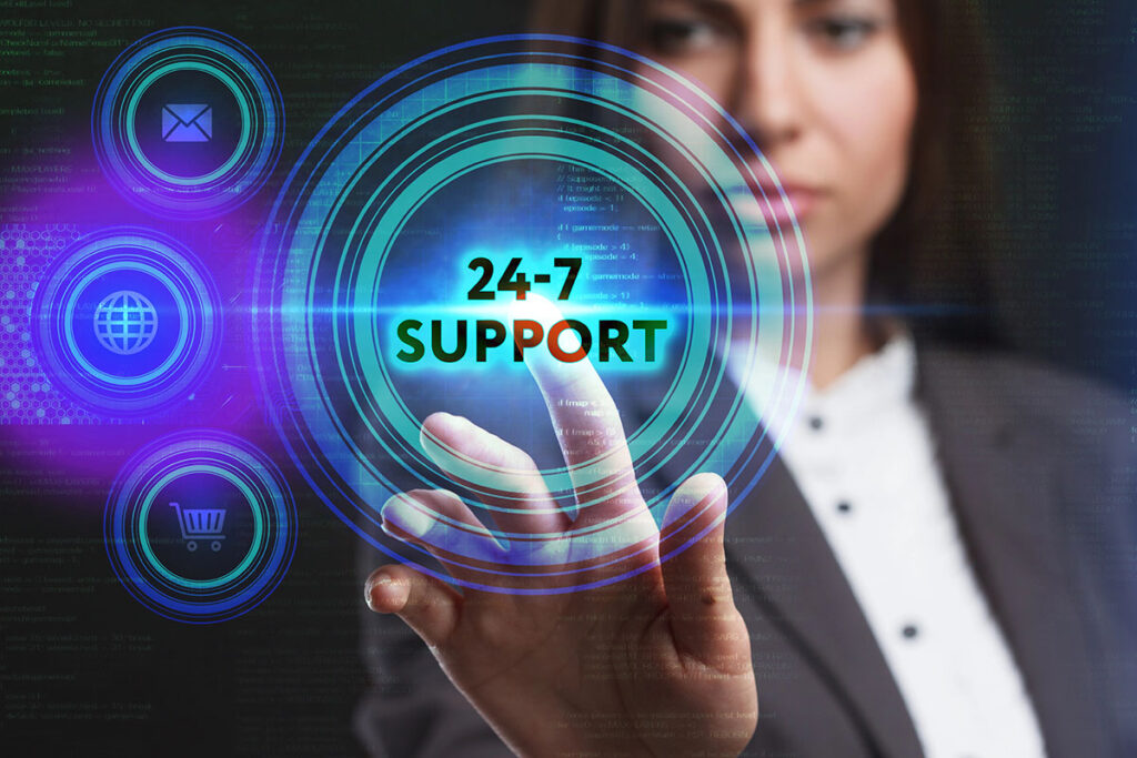 A business professional in a suit points toward a digital button labeled "24-7 SUPPORT," surrounded by various icons, including an envelope, globe, and shopping cart, against a dark, tech-themed background.