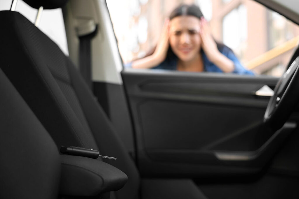 View from inside a vehicle showing a car key fob left on the driver's seat, while a stressed woman holds her head outside the window after locking herself out.